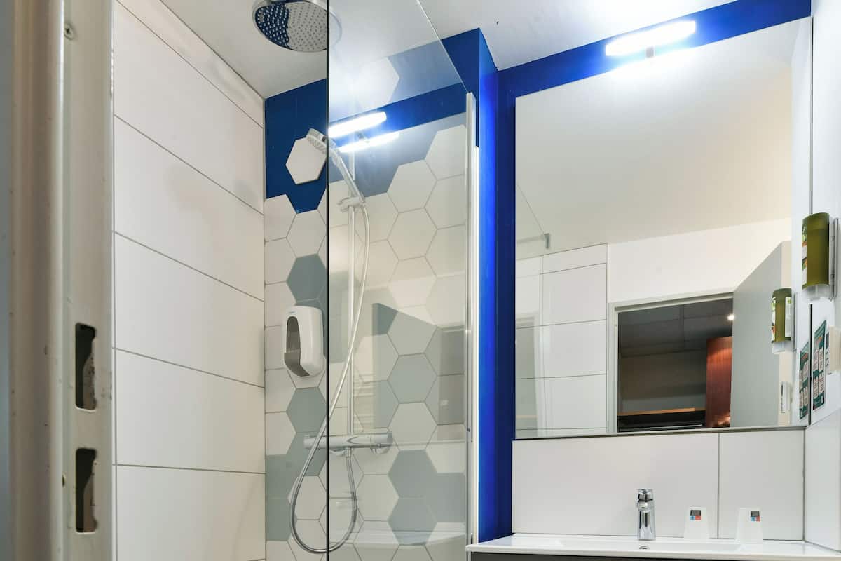 Un baño moderno con ducha de vidrio, tocador con espejo y lavamanos.