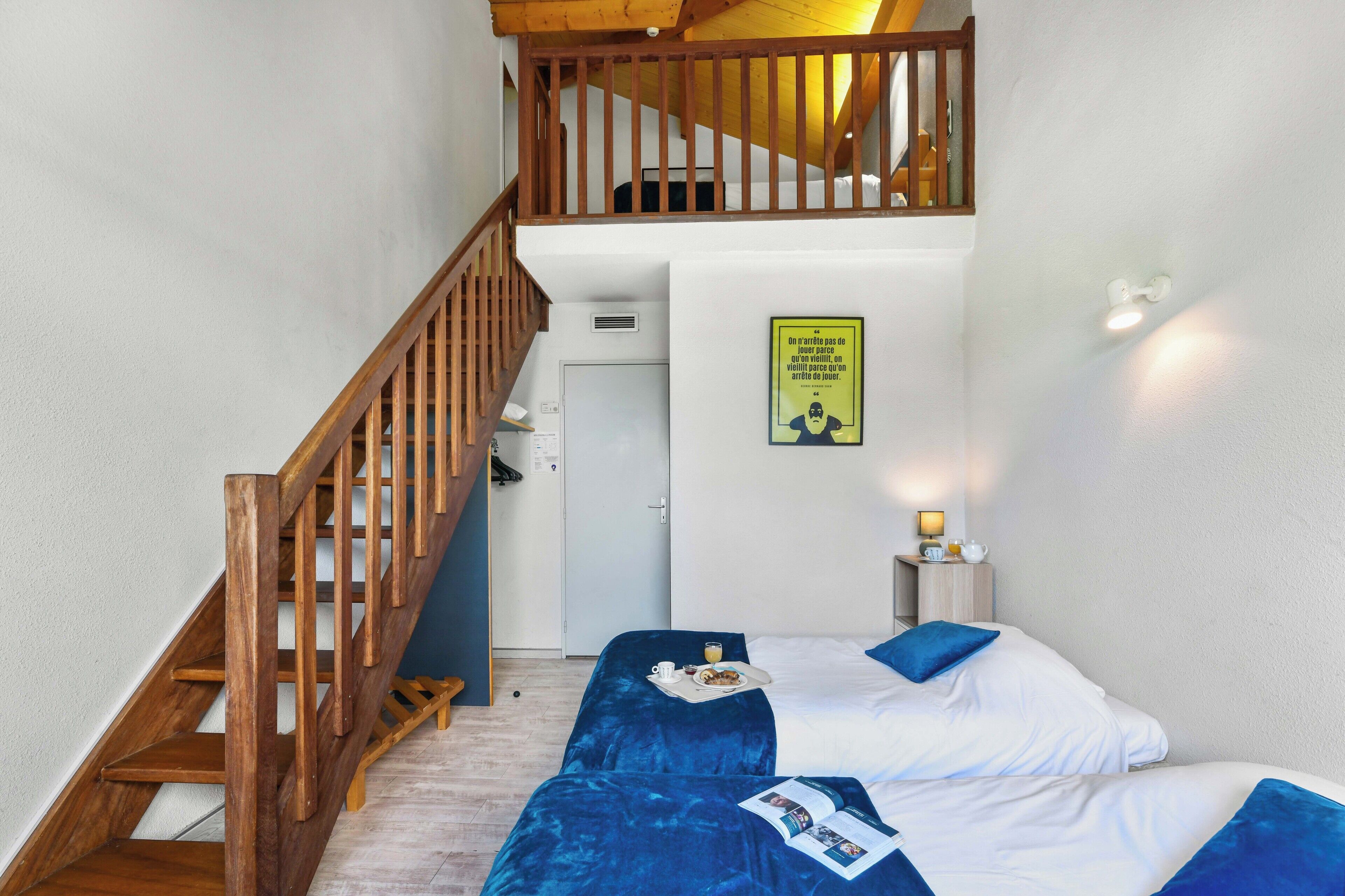 Une chambre avec deux lits, un escalier en bois et une petite table avec une lampe.