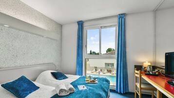 Une chambre d’hôtel avec un lit, un bureau équipé d’un ordinateur, une fenêtre avec des rideaux et une vue sur une piscine.