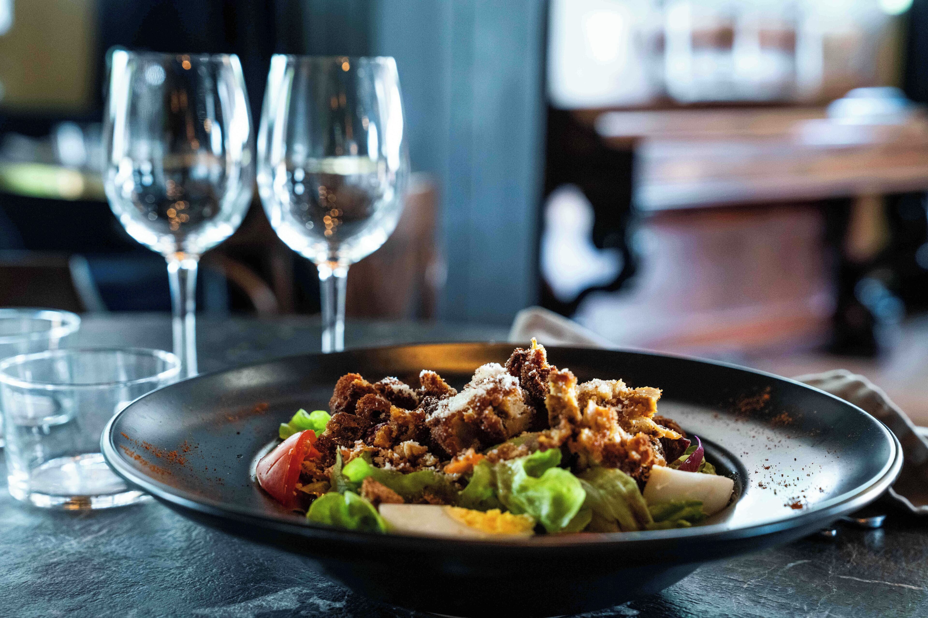 A plate of food with a variety of ingredients, accompanied by two glasses of water and a small glass.