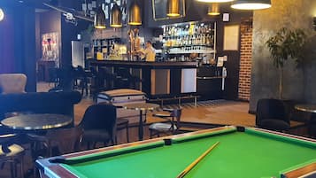 Et billardbord i en bar, med en bartender bag disken.
