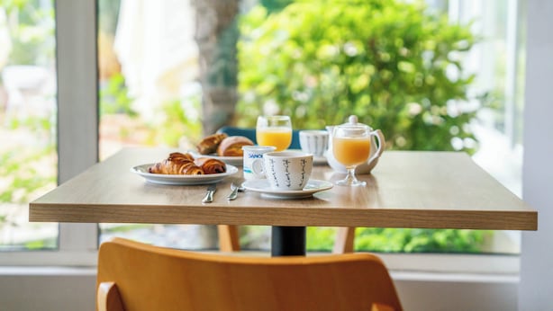 Een ontbijttafel met croissants, een kopje en een glas sinaasappelsap.