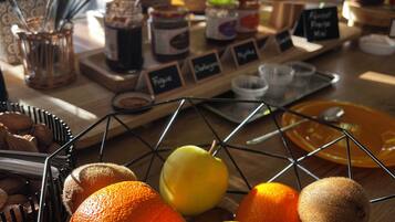 Una cesta de frutas con naranjas, limones y kiwis sobre una mesa de madera.