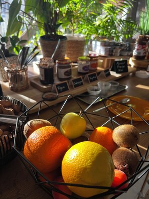 Una cesta de frutas con naranjas, limones y kiwis sobre una mesa de madera.