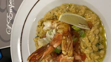 Een bord seafood risotto met een partje citroen en groene bieslook.