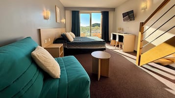 Una habitación de hotel con cama, sofá, mesita, escritorio y televisor.