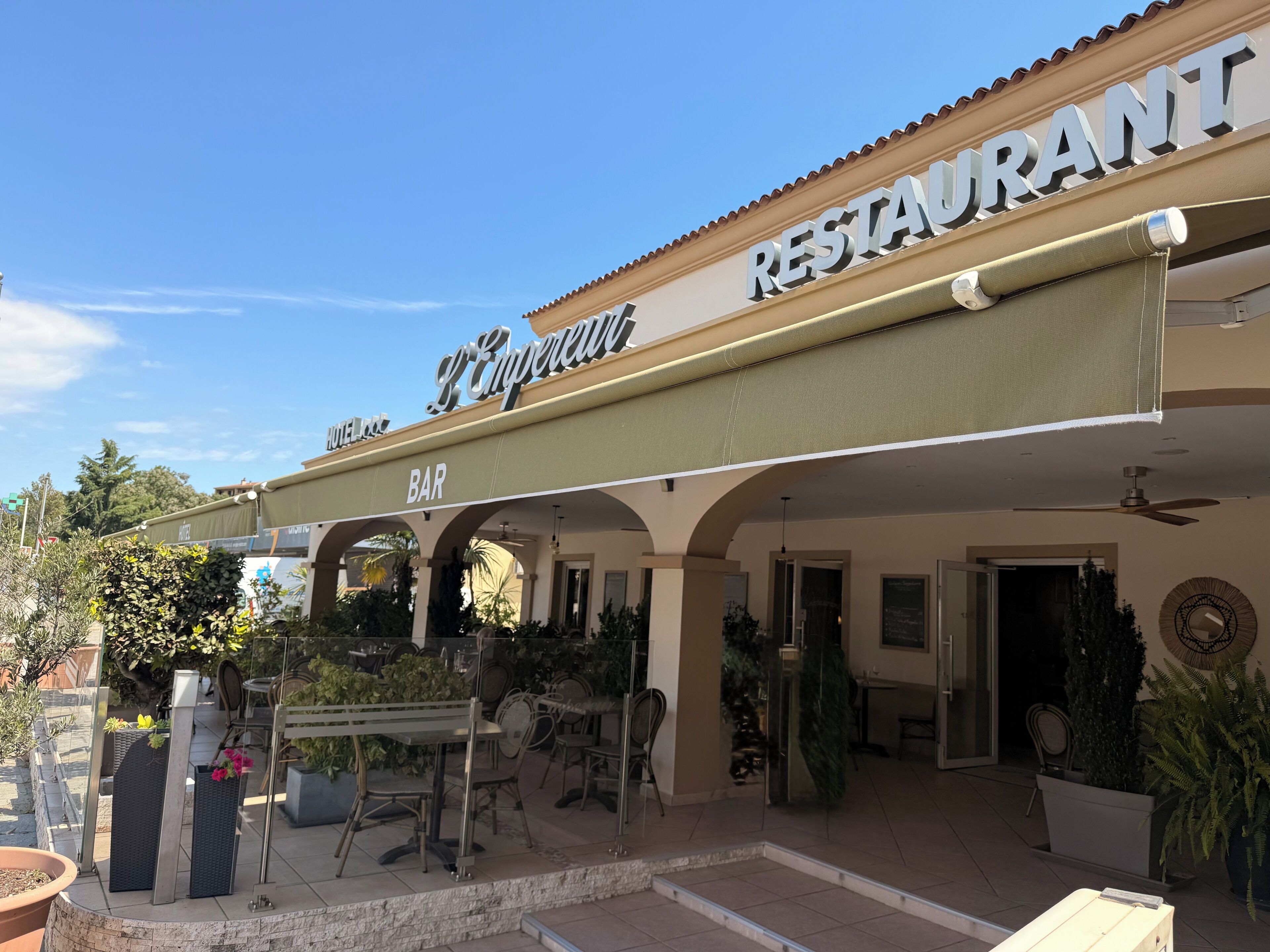 A restaurant with outdoor seating, a bar, and a sign indicating it is part of a hotel.