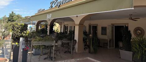 A restaurant with outdoor seating, a bar, and a sign indicating it is part of a hotel.