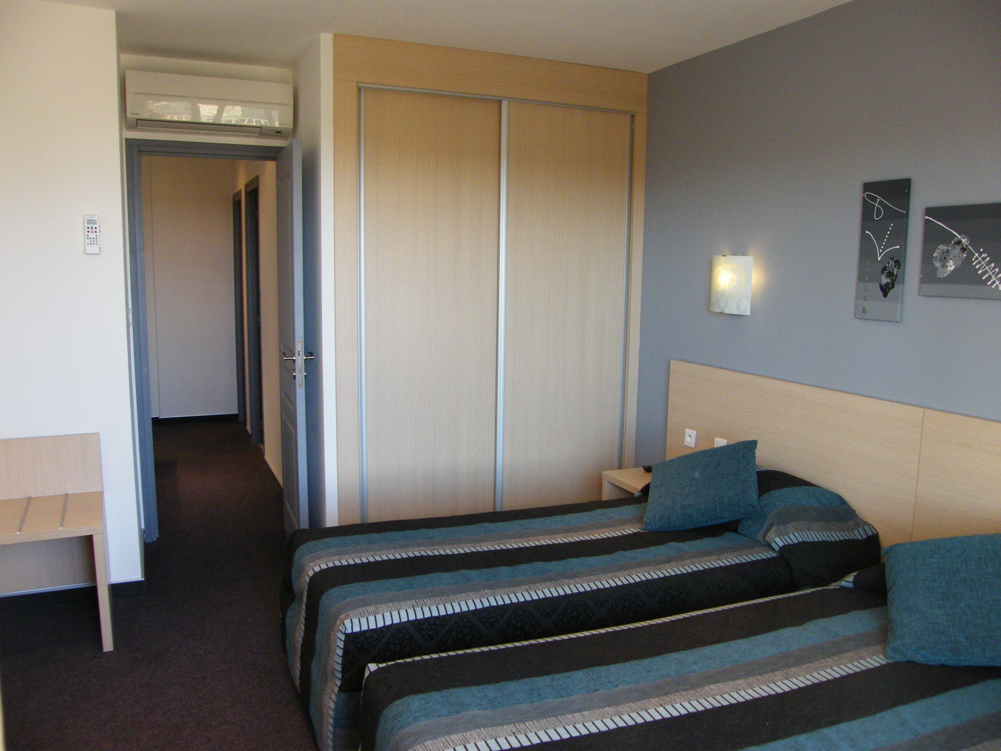Une chambre d’hôtel avec deux lits, un bureau, une armoire et une table de chevet.