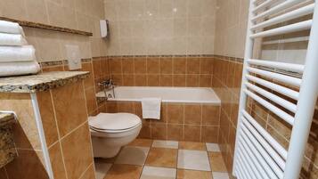 A bathroom with a toilet, bathtub, and a towel rack.