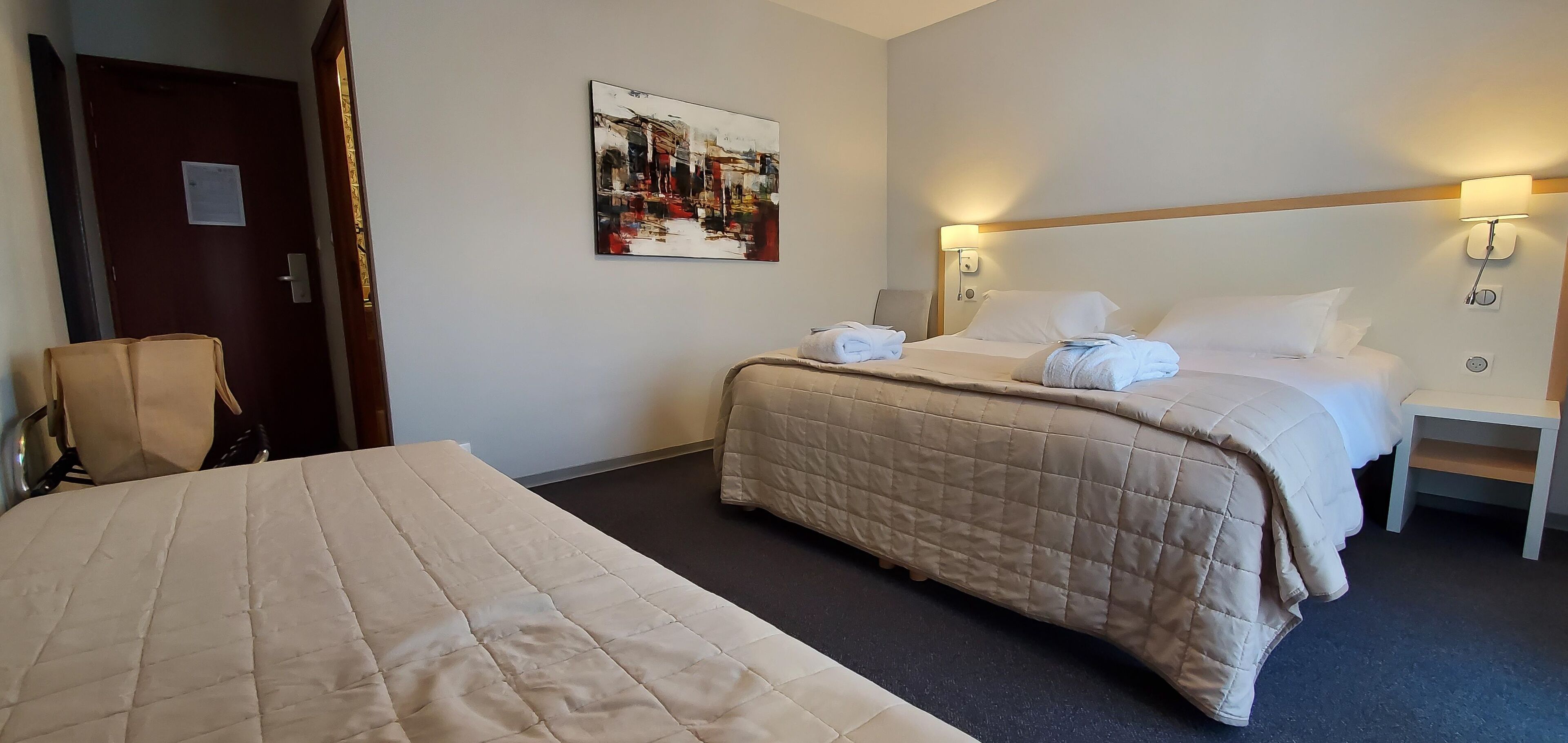 Ein Hotelzimmer mit zwei Betten, einem Bild an der Wand und einem Nachttisch mit einer Lampe.