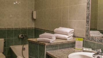 A bathroom with a toilet, bathtub, sink, and a mirror with decorative tiles.