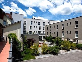 Un edificio moderno con varios pisos, balcones y un patio con vegetación.
