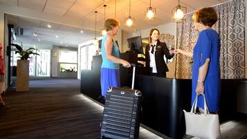 A reception area with a black counter, a potted plant, and a wooden floor.