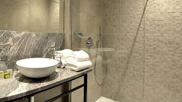 A modern bathroom with a glass-enclosed shower, a marble sink, and a glass shower door.