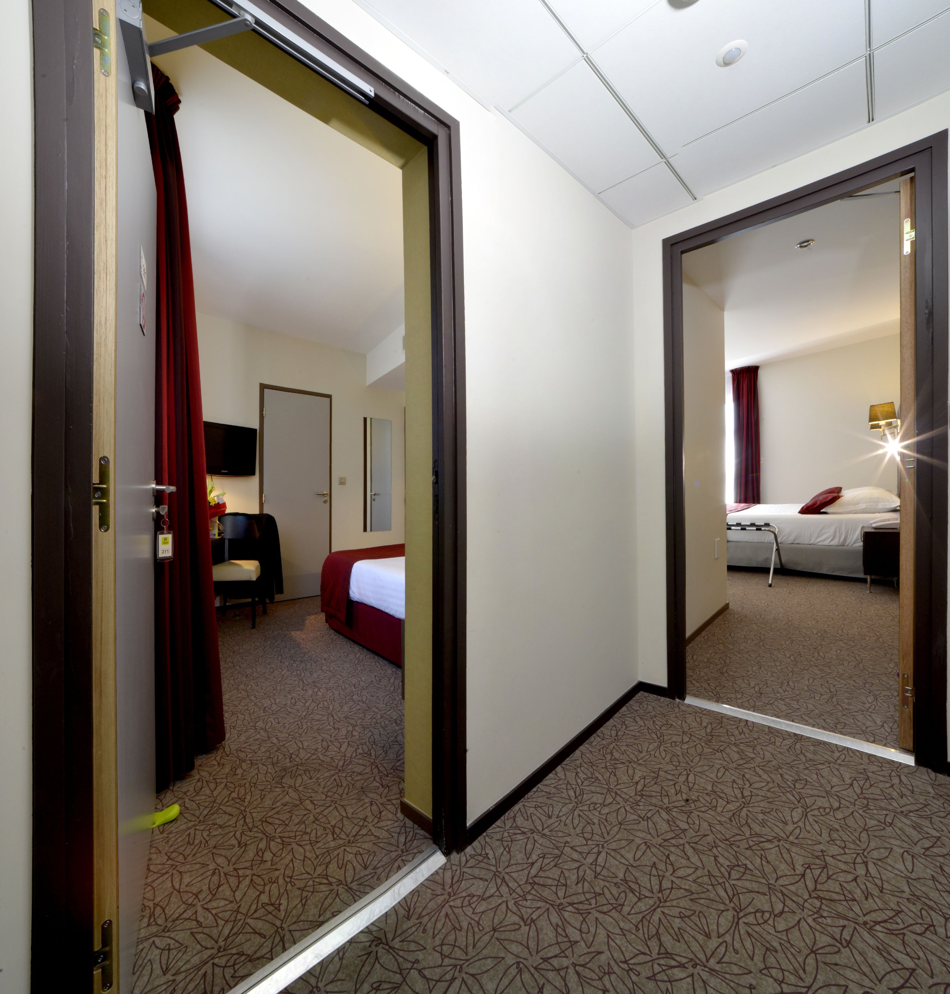 A hotel room with a bed, a desk, a chair, and a television.