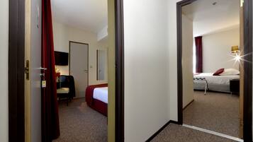 A hotel room with a bed, a desk, a chair, and a television.