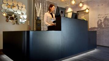 A reception desk with a modern design, a large mirror wall, and a patterned curtain.