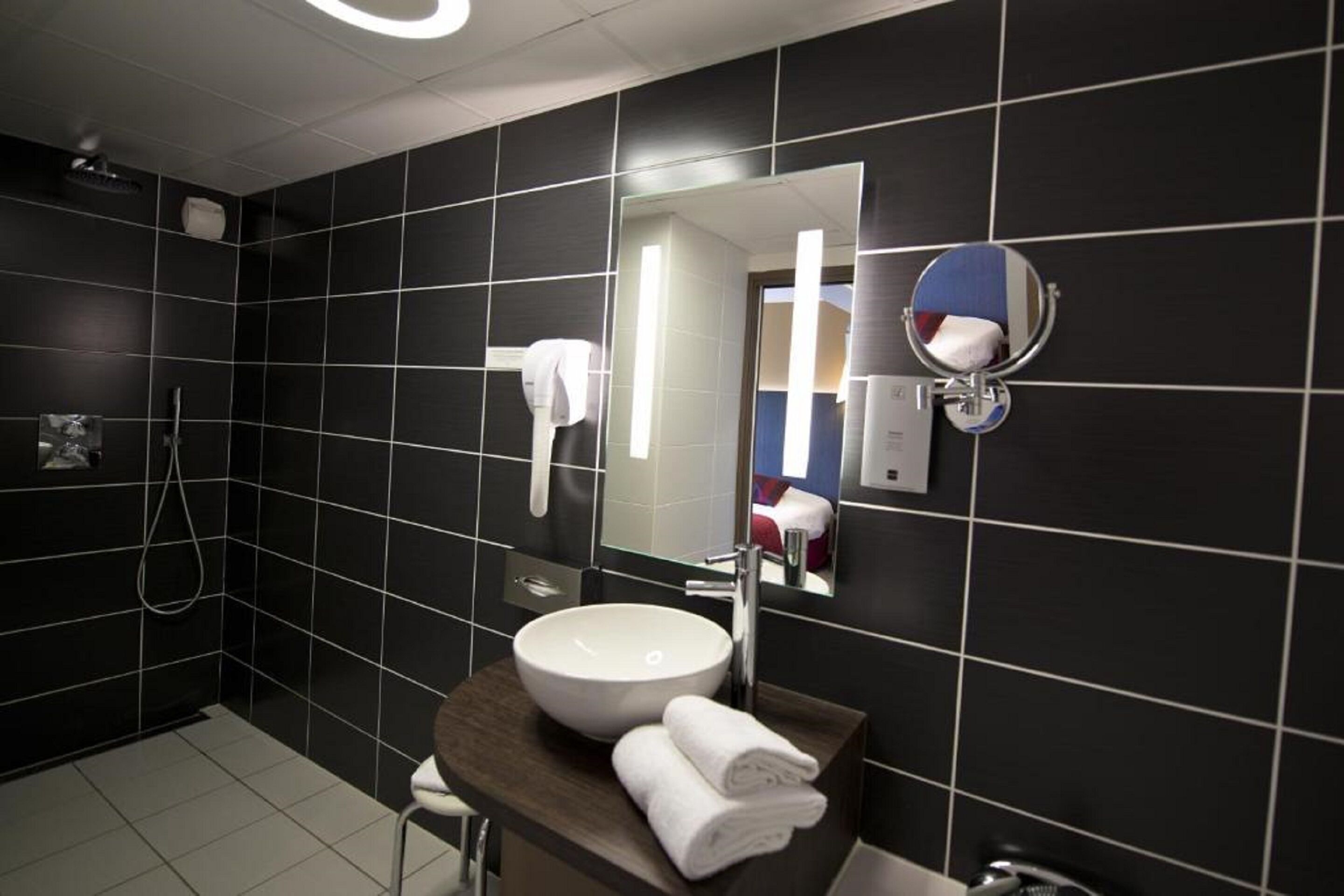 Un baño moderno con un espejo grande, un lavabo blanco y un perchero para toallas.