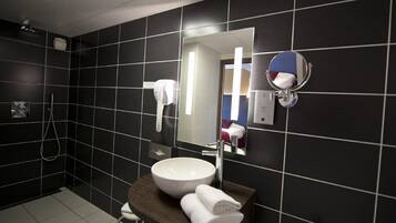 A modern bathroom with a large mirror, a white sink, and a towel rack.
