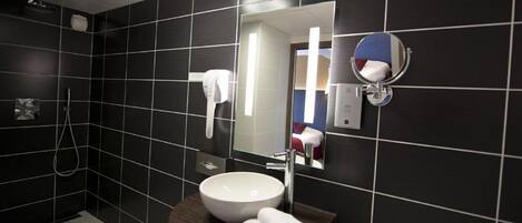 Un baño moderno con un espejo grande, un lavabo blanco y un perchero para toallas.