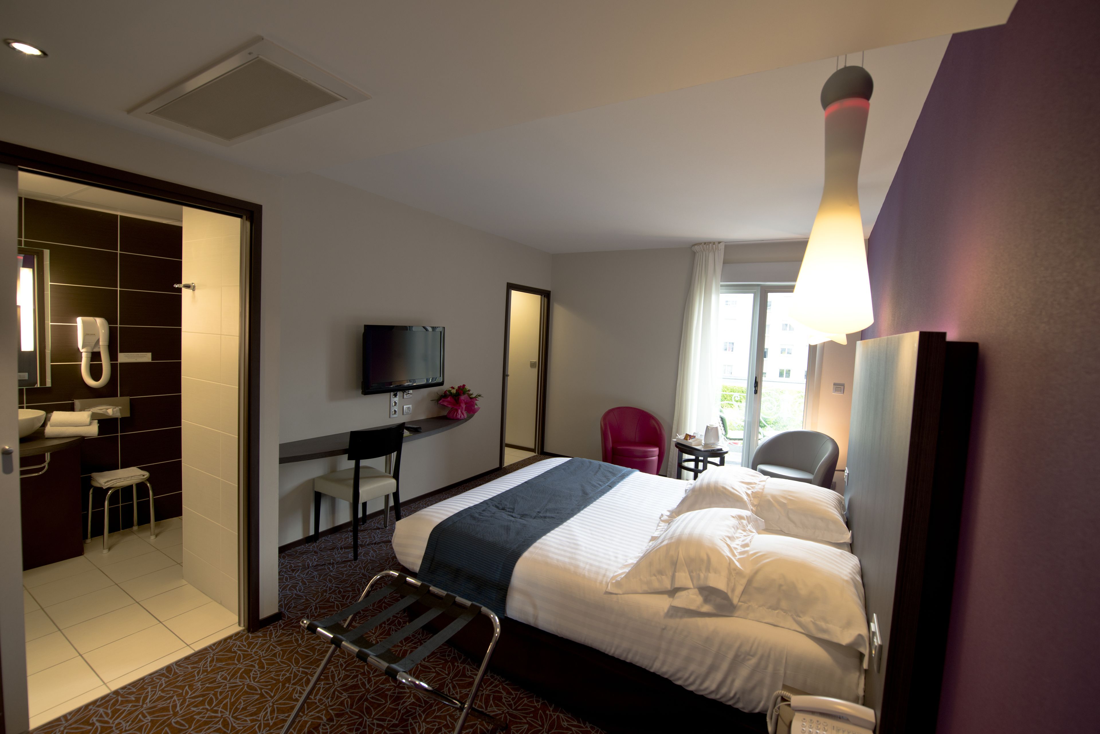 Une chambre d’hôtel comprenant un lit, un bureau, une chaise, une télévision et une salle de bain.
