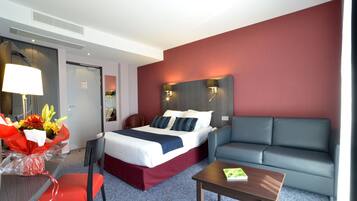 A hotel room with a bed, a sofa, a table, and a chair.