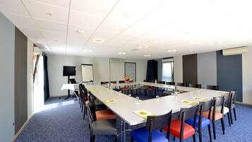 A conference room with a long table, chairs, a whiteboard, and a projector screen.
