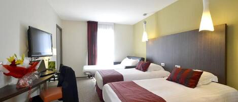 A hotel room with two beds, a desk with a TV, and a chair.