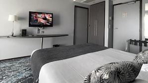 Una camera d'albergo con un letto, una TV su un mobile, una scrivania e un armadio.