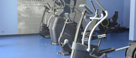 Un gimnasio con bicicletas estáticas y una frase motivacional en la pared.