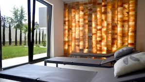 Una stanza con due poltrone reclinabili, un'uscita con porta in vetro e una parete con motivo decorativo.