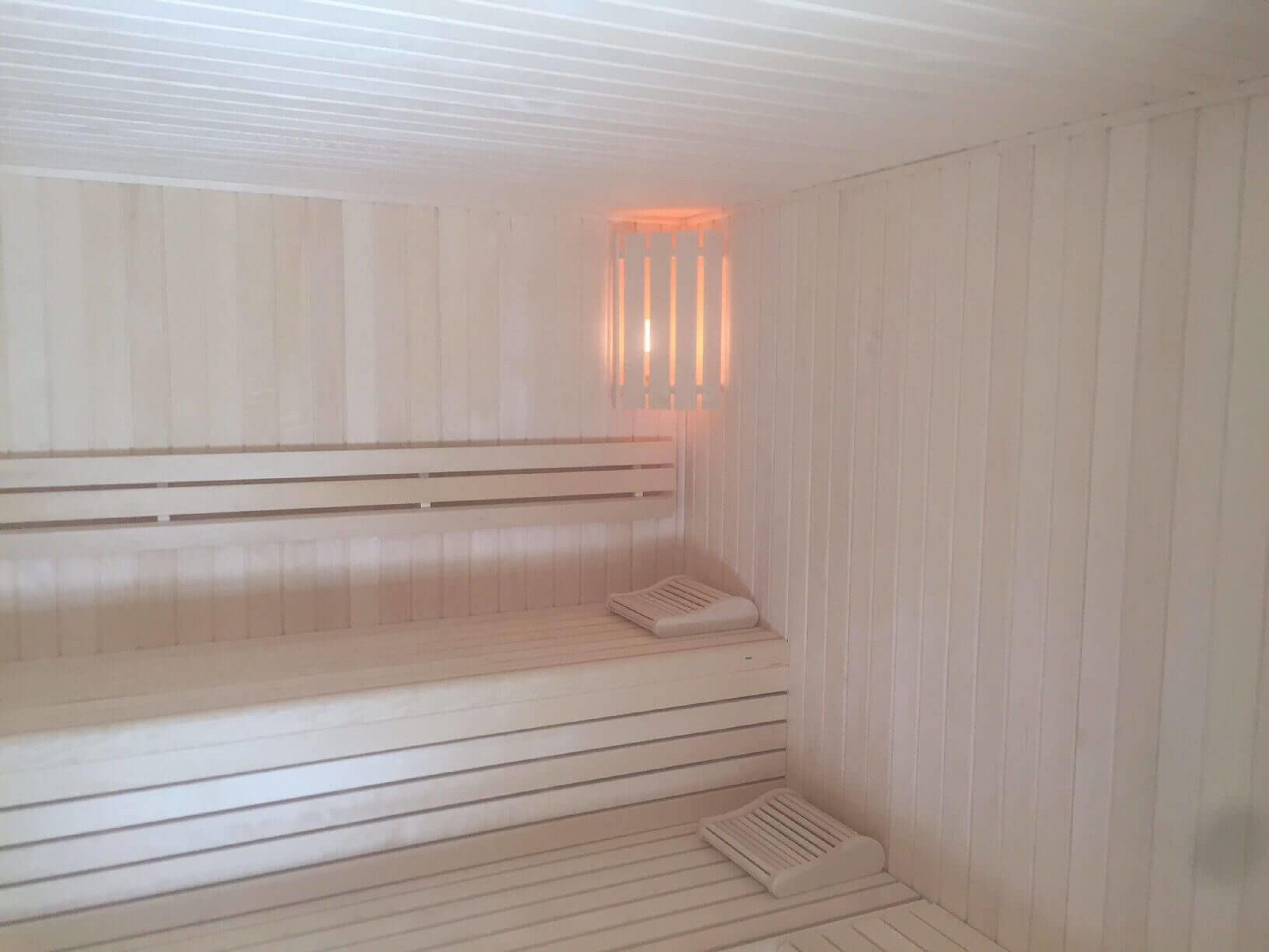 Un sauna avec des bancs en bois et un plancher incliné.