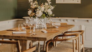 A dining area with a wooden table set for four, surrounded by wicker chairs. - Le Goyen (Audierne)