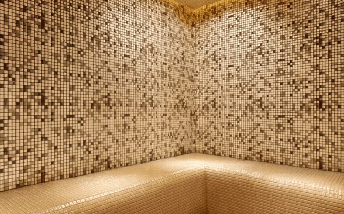 A room with a tiled mosaic wall and a cushioned bench.