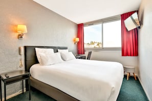 A hotel room with a large bed, two bedside lamps, a desk with a chair, a small stool, and a window with red curtains. - Hôtel Bristol Périgueux Centre (Périgueux)