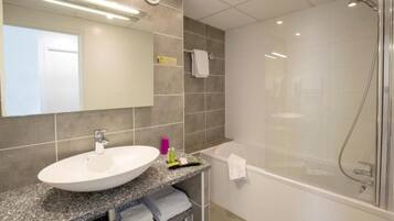 Une salle de bain moderne avec un lavabo blanc, une douche à parois de verre et un miroir au-dessus du lavabo.