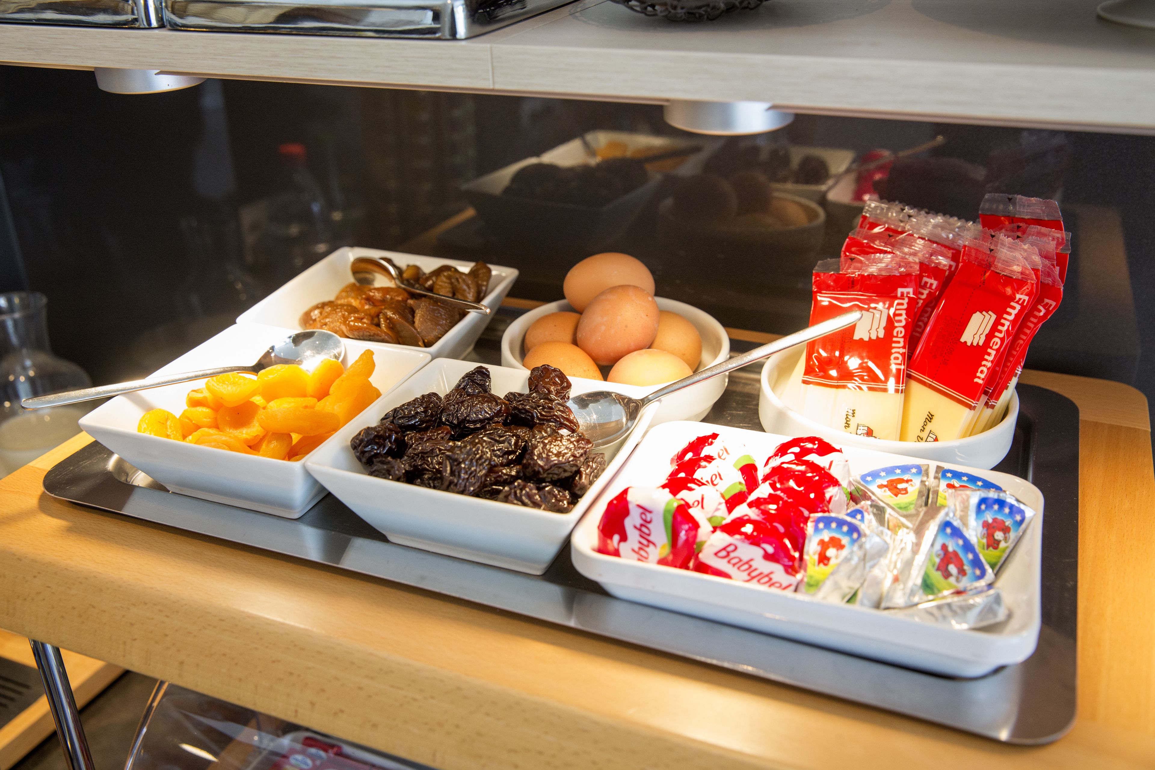En frukostbuffé med ett varierat utbud av mat, inklusive frukt, ägg och förpackade snacks.