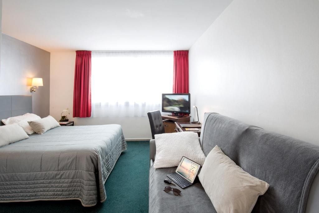 A hotel room with two beds, a desk with a computer, and a television.