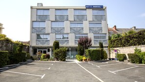 A hotel with a modern facade, multiple windows, and a parking lot in front. - Hôtel Bristol Périgueux Centre (Périgueux)
