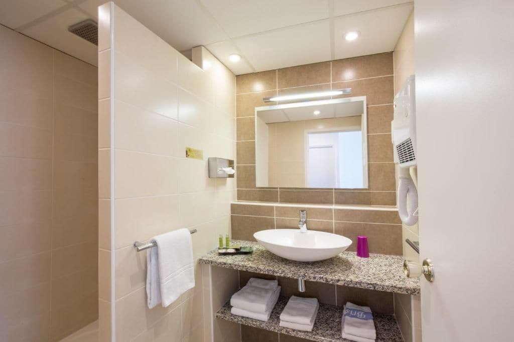 A modern bathroom with a white sink, a mirror, and a towel rack.