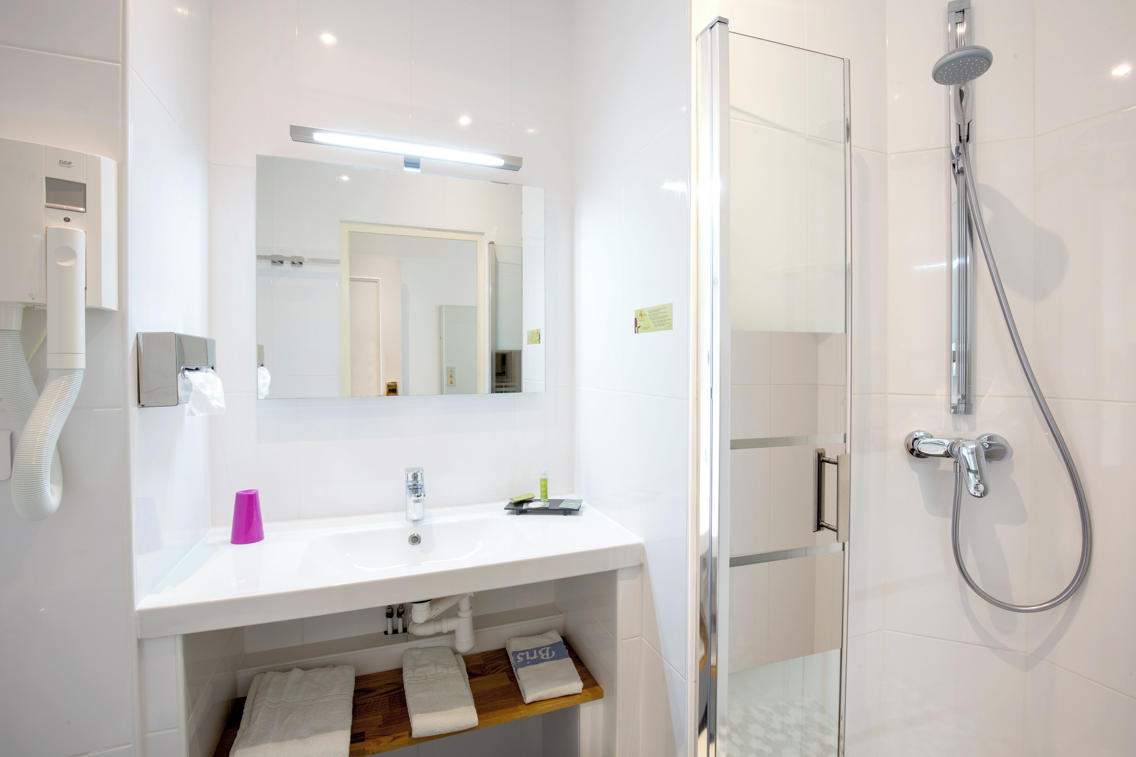 Een moderne badkamer met een wit wastafelmeubel, spiegel en een douchecabine van glas.