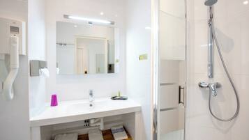 Een moderne badkamer met een wit wastafelmeubel, spiegel en een douchecabine van glas.