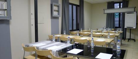 A conference room with tables, chairs, and a whiteboard.