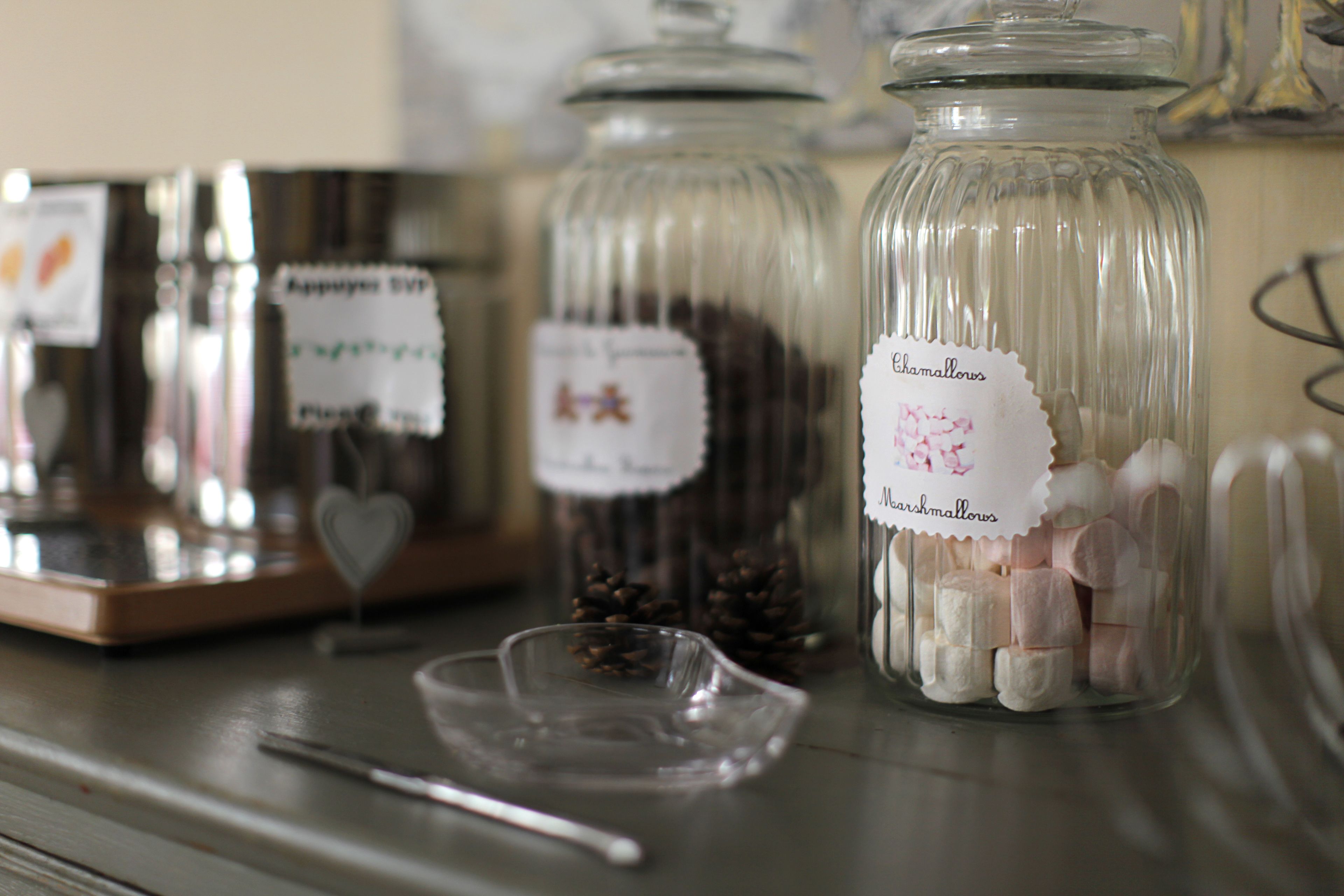 Glass jars with labels on a table, one labeled "Chamallows".