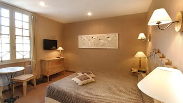A hotel room with a bed, a desk, a chair, a television, and wall-mounted lamps.