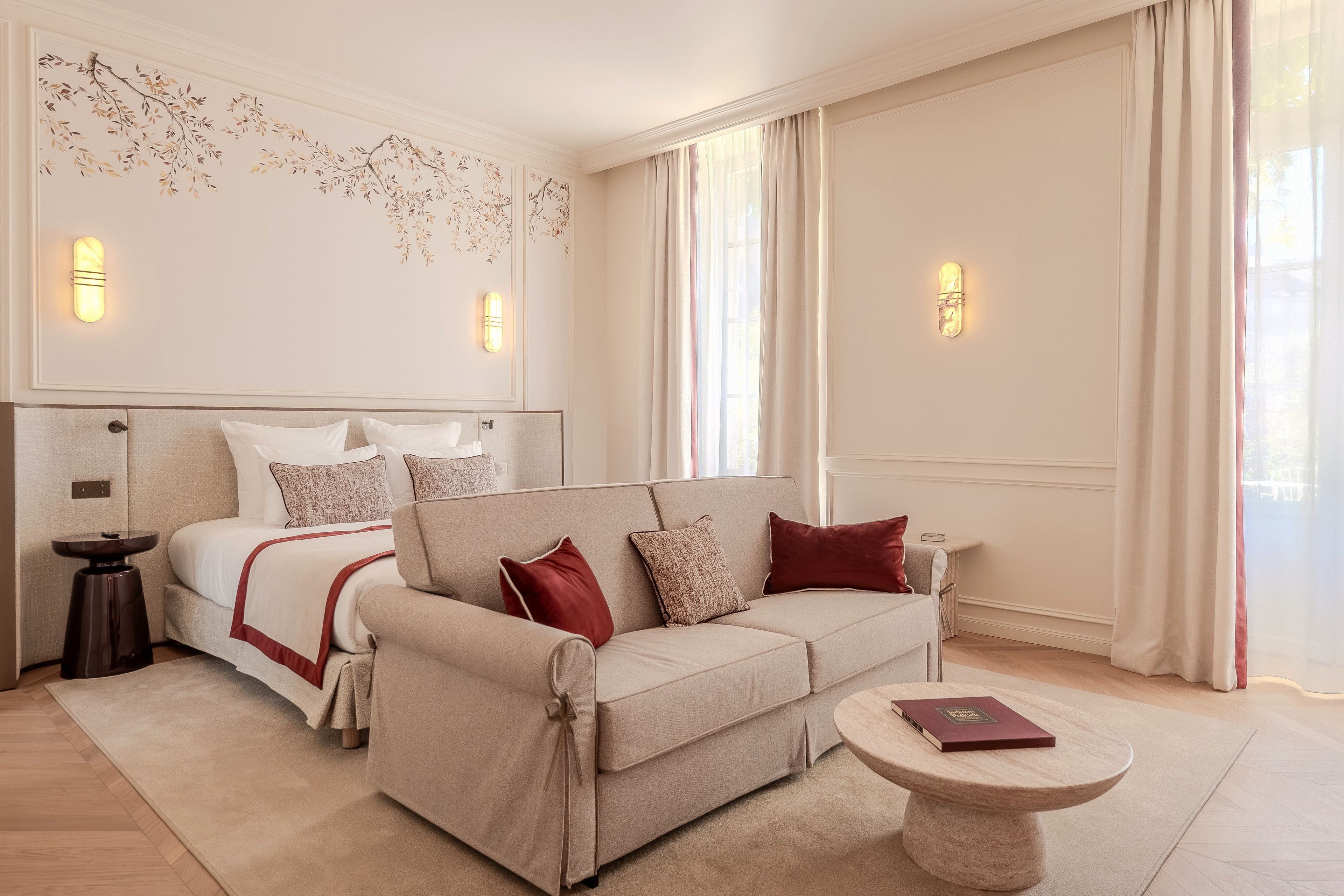 Una habitación de hotel con cama, sofá, una mesita y decoración en la pared.