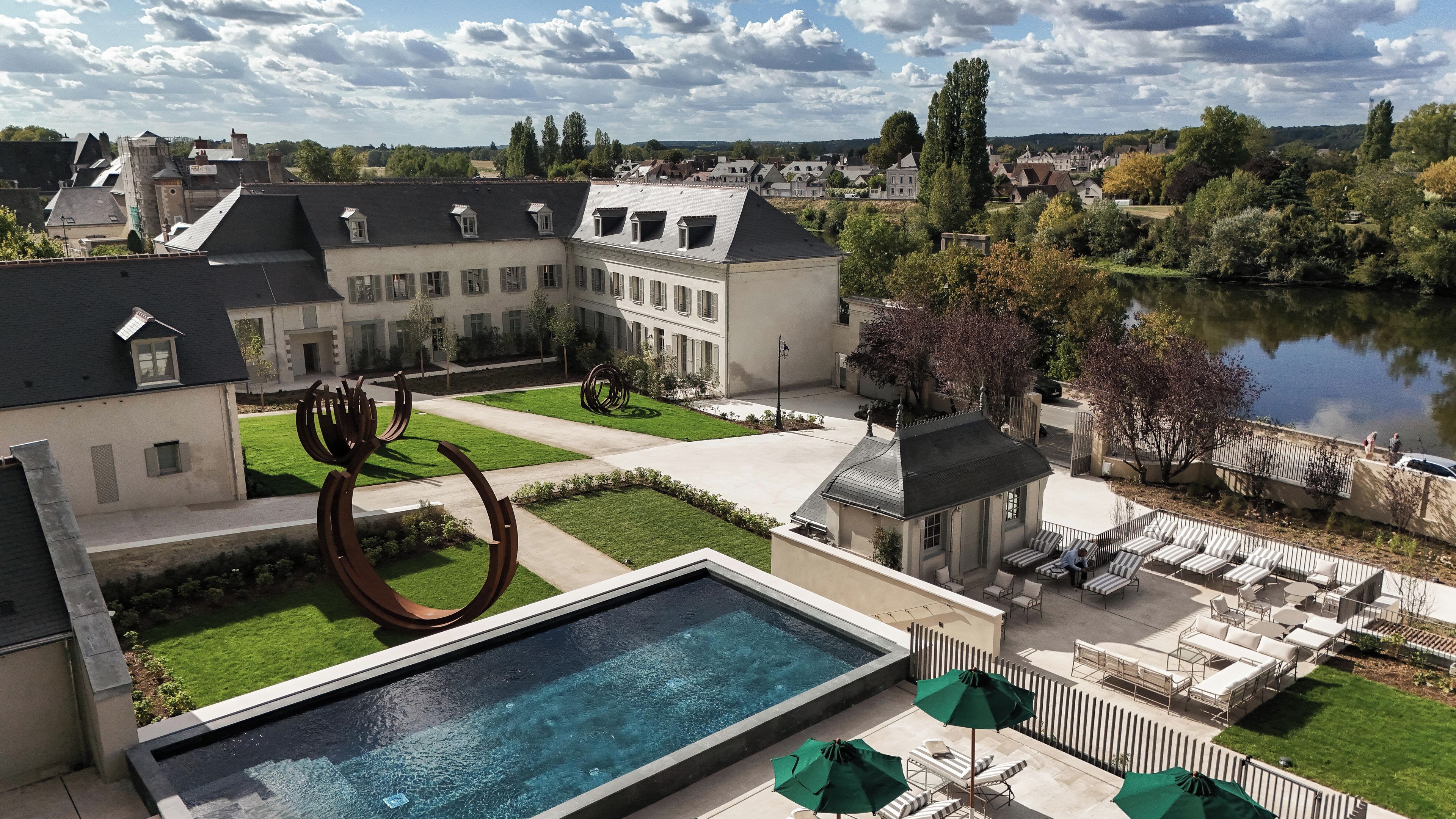 A courtyard with a swimming pool, outdoor seating, and a view of a lake.