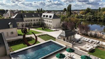 A courtyard with a swimming pool, outdoor seating, and a view of a lake.