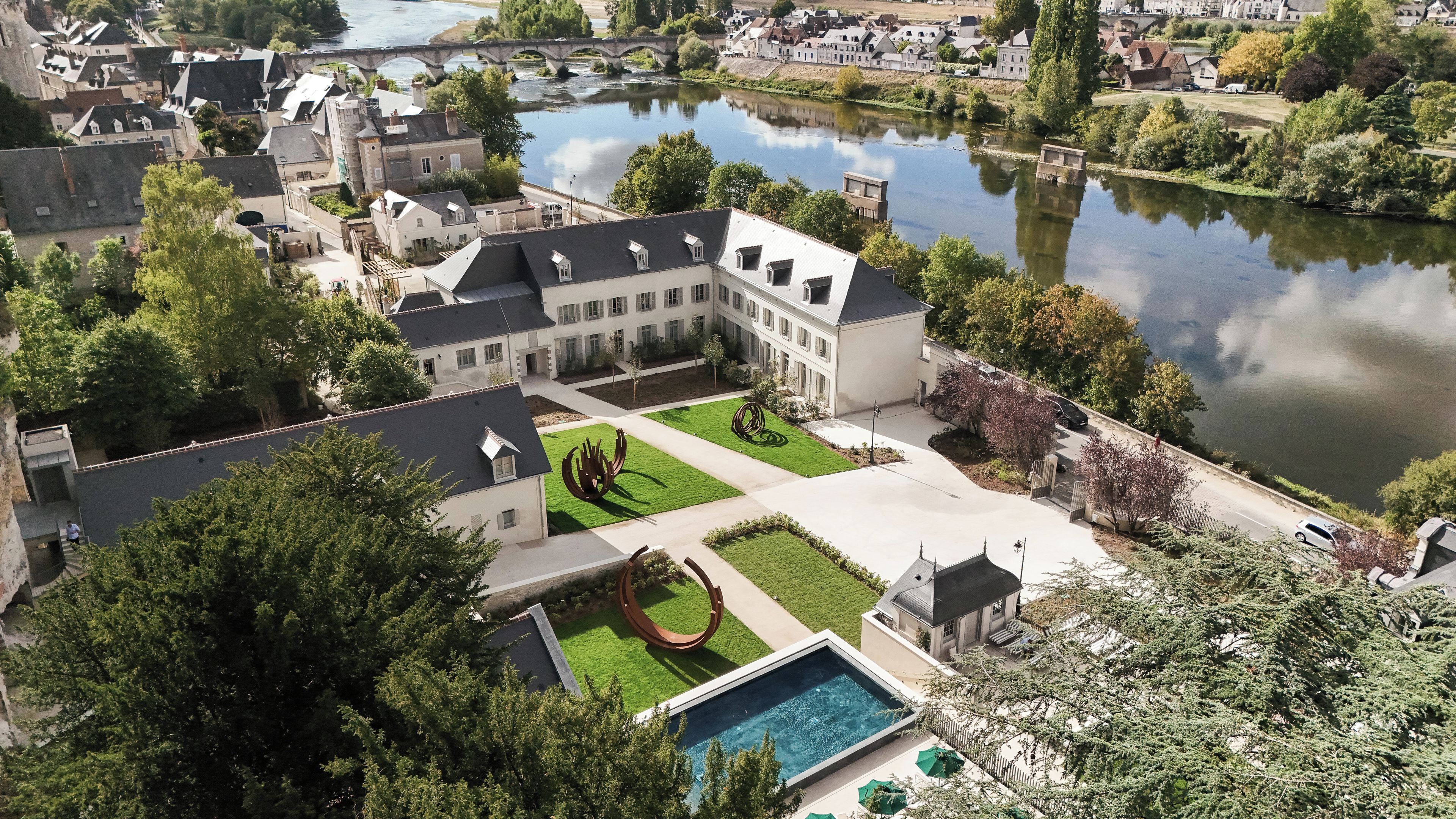 A courtyard with a swimming pool, surrounded by buildings and a river.